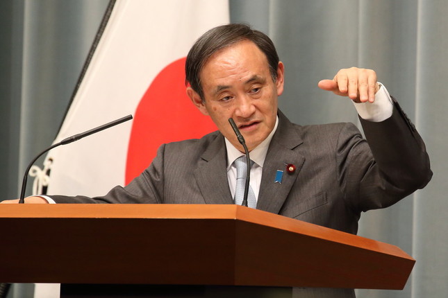 菅義偉官房長官は、過去の消費税率引き上げで「結果として税収が下がってきた」とジェスチャーを交えて説明した