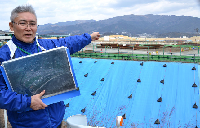 震災当時の津波被害を説明する河野正義さん。写真右奥に「奇跡の一本松」が見える
