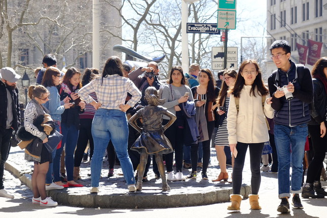 「恐れを知らぬ少女像」の前で記念撮影をするために群がる人たち