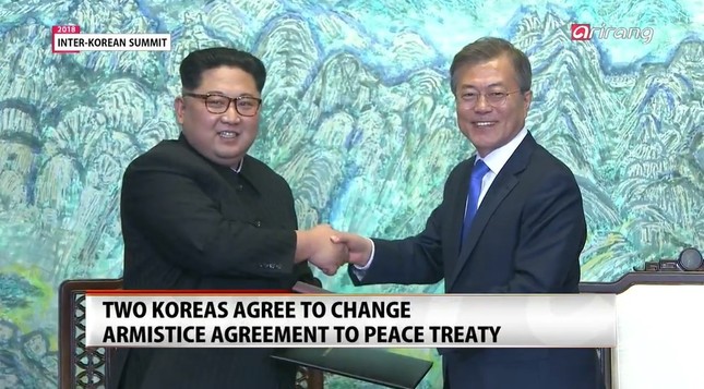 「板門店宣言」に署名する両首脳。「完全な非核化」を目指すとした（画面は韓国・アリランテレビから）