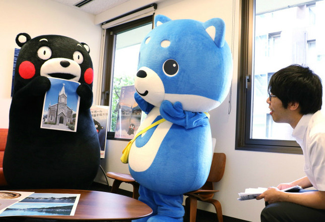 編集部員に﨑津集落の魅力を伝えるくまモン