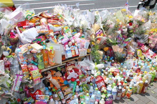 池袋の事故現場には、花束のほか菓子や飲み物なども続々と供えられた（2019年4月23日撮影）