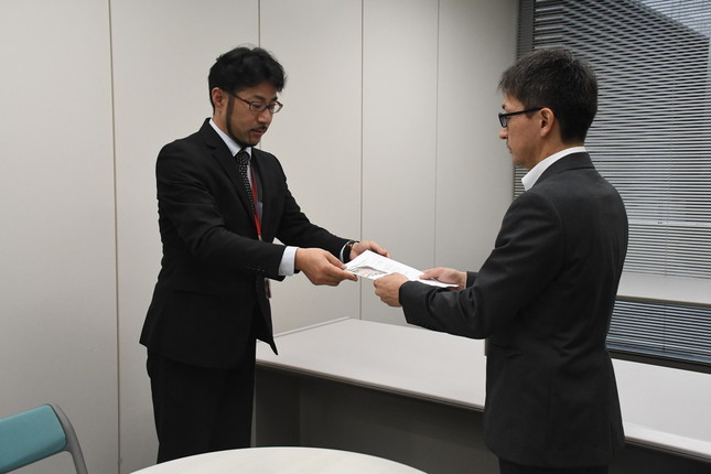 CD-ROMを手渡す畠山さん（左）