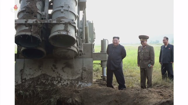 ランチャー下部にエンジンの推力で穴が開いた様子を金正恩氏が眺めている。4本あるランチャーのうち、1本には蓋がついた状態だ（写真は朝鮮中央テレビから）