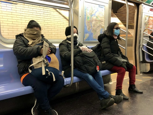 ニューヨークの地下鉄で、マスクやマフラーで顔を覆う乗客たち