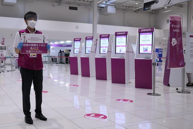関西空港のチェックイン機では、係員が間隔を開けて並ぶように呼びかけた