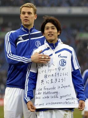 東日本大震災でメッセージを贈る内田篤人選手（右）とマヌエル・ノイアー選手（写真：AP/アフロ、2011年3月12日撮影）