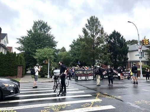 ニューヨークで社会主義を唱えるデモ行進が通りかかる交差点で自転車を止め、デモ隊を誘導する人たち（2020年8月、筆者撮影）