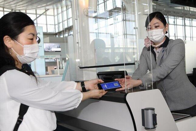 実証実験に協力した乗客（左）が「コモンパス」で「デジタル陰性証明書」を空港係員に見せてチェックインした