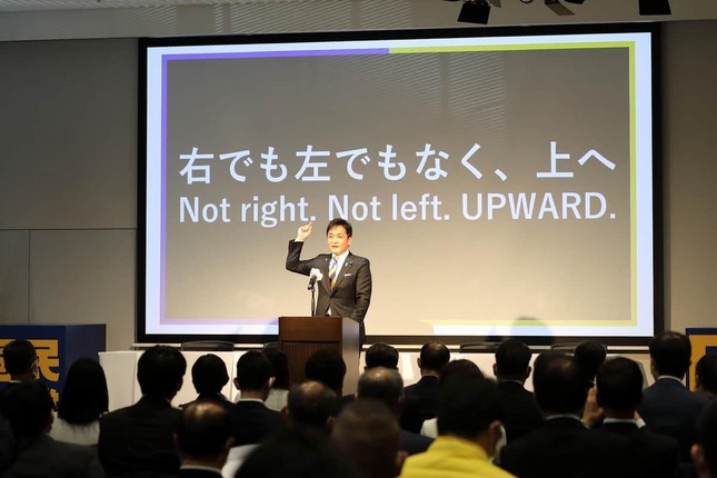 定期党大会であいさつする国民民主党の玉木雄一郎代表。スクリーンに「右でもなく左でもなく、上へ」の標語を掲げた