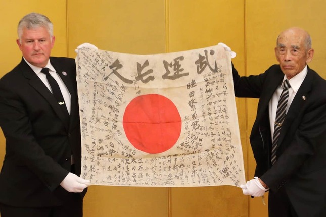 陸田繁義さんの遺品の日章旗は靖国神社で遺族に返還された。左からUSSレキシントン博物館のスティーブ・バンタ館長、長男の敏弘さん