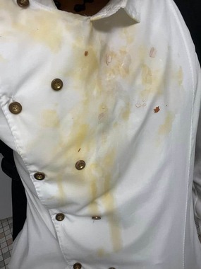 エイジさんがXで投稿した写真。生卵で汚れたコックコートのアップで、広範囲にベッタリと黄色いシミができている