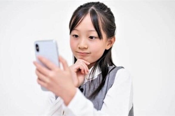 スマホを持つ小学生（写真はイメージ）