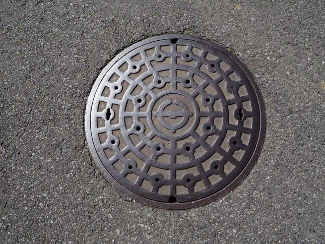光を照り返すマンホール蓋のイメージ