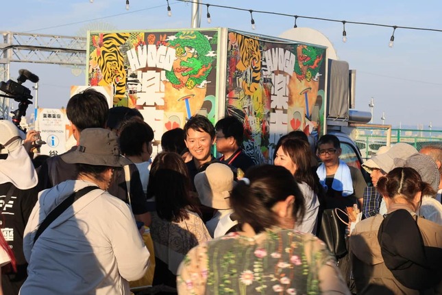 楽市楽座のデコトラ前で写真撮影に応じる斎藤元彦知事（2日、兵庫県尼崎市）