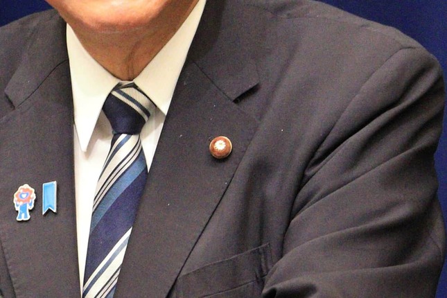 議員バッジのあたりを拡大。白い粉のようなものが見える