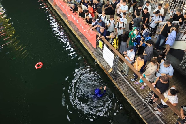 飛び込んだ「ミャクミャク」のコスプレをした人物。頭部は外れ、川に浮かんだ（7日、大阪市中央区）