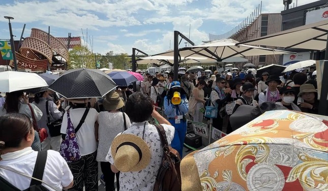 入場列の外で待機する来場者に移動するように呼び掛ける警備員（18日、大阪市此花区）