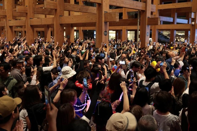 閉幕イベントを撮影しようとカメラを向ける来場者（13日20時39分、大阪市此花区）