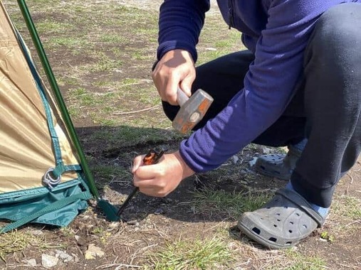 ペグを打ち付けテントを張る様子（画像はイメージ）
