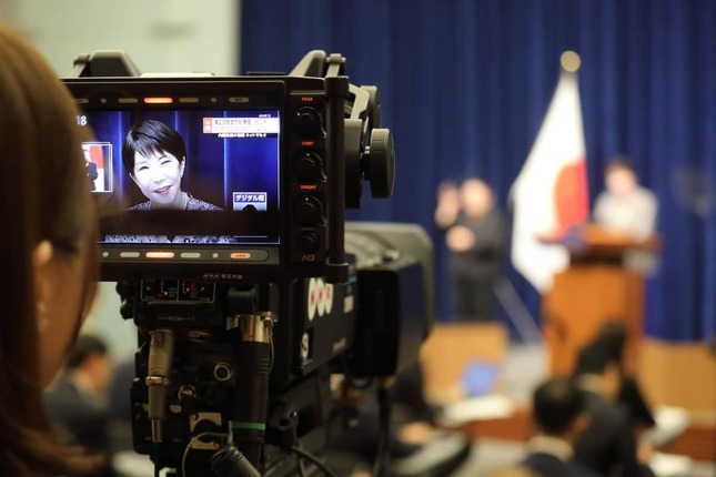 テレビカメラのモニターに映る高市首相。会見の様子は各社が中継した