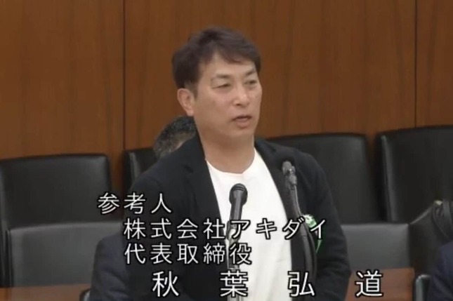 参考人として意見を述べるスーパー「アキダイ」の秋葉弘道社長。エプロン姿は実現しなかった（衆院インターネット中継より）