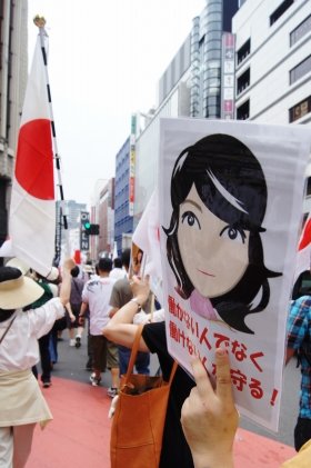 片山議員の似顔絵などが描かれたプラカードを掲げて行進するデモ隊