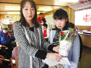 阿部裕子さん（左）は、ミニバラの鉢植えと群馬県の女性からのメッセージ「花からエネルギーをもらって元気になってください」を受け取り、「お花が大好きなので、とても嬉しいです。娘と一緒に大切に育てます。バラは株分けできるので、これから増やしていきたいです」。裕子さんは、震災当時必死で津波から逃れましたが、あと数分逃げるのが遅ければだめだっただろうとのこと。重度の知的障害のある娘の美沙希さん（右）とは何日も連絡が取れなかったそうです。（2012年5月13日　宮城県石巻市）