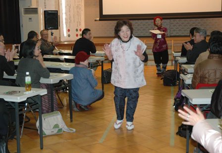 和服から仕立て直した洋服を着て観客席を歩くお年寄りのモデル＝2013年12月1日、大槌町中央公民館