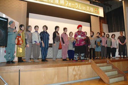 舞台に勢ぞろいした仮設住宅に住むモデルの人たち。中央が小赤澤直子さん＝2013年12月1日、大槌町中央公民館