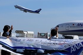 ANAスタッフが横断幕で離陸する747を見送った