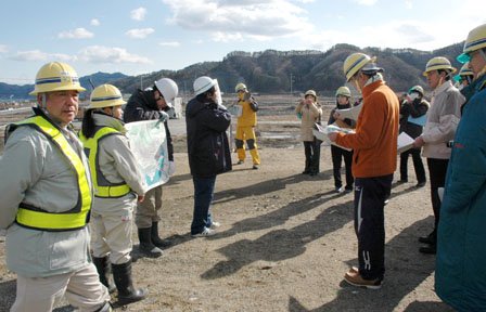 町方地区の先行盛り土の上で見学者に復興計画を説明する工事関係者＝2014年2月7日