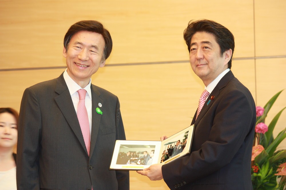 安倍首相と会談する韓国の尹炳世（ユン・ビョンセ）外相（左）。こじれた日韓関係の責任が「日韓双方にある」という論調が韓国メディアでも目立つ（写真：Yonhap/アフロ）