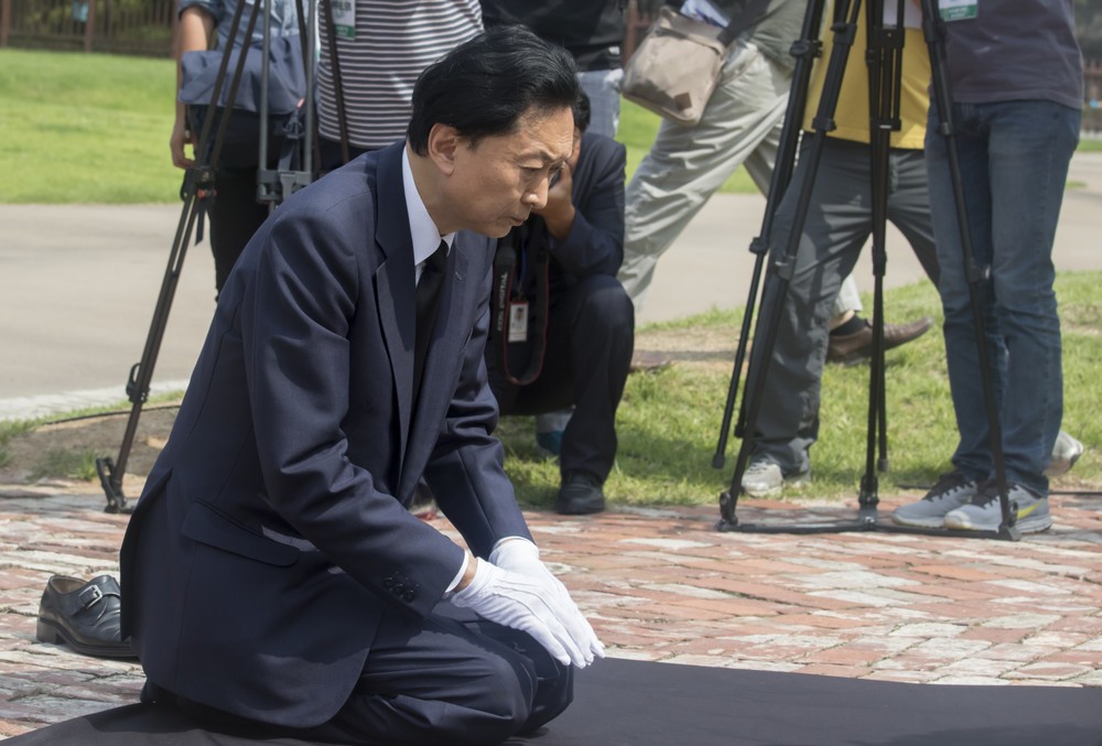 西大門刑務所跡地の記念碑を前にひざまづいて頭を下げる鳩山由紀夫元首相（写真：Lee Jae-Won/アフロ）