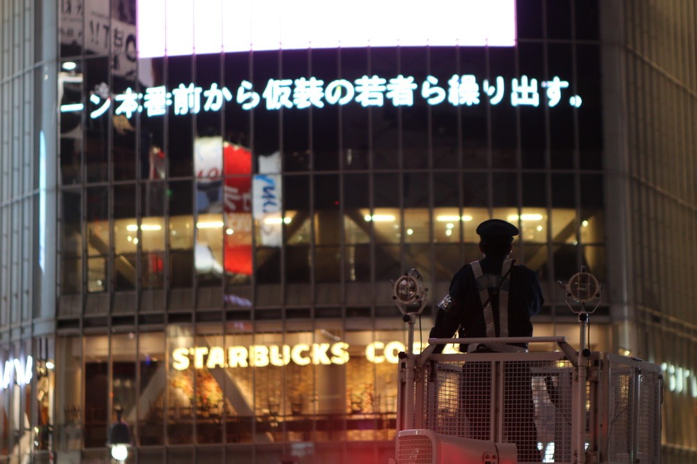 交通整理に当たる「DJポリス」。奇しくも大型ビジョンには、この渋谷のお祭り騒ぎのニュースが流れていた