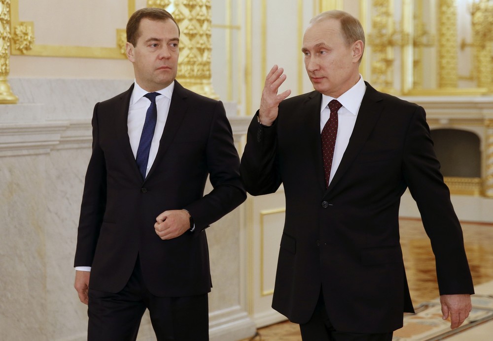 2013年12月12日、ロシアのプーチン大統領（右）がモスクワ・クレムリンでの年次教書演説を終えてメドベージェフ首相と会話を交わす（写真：代表撮影/AP/アフロ）