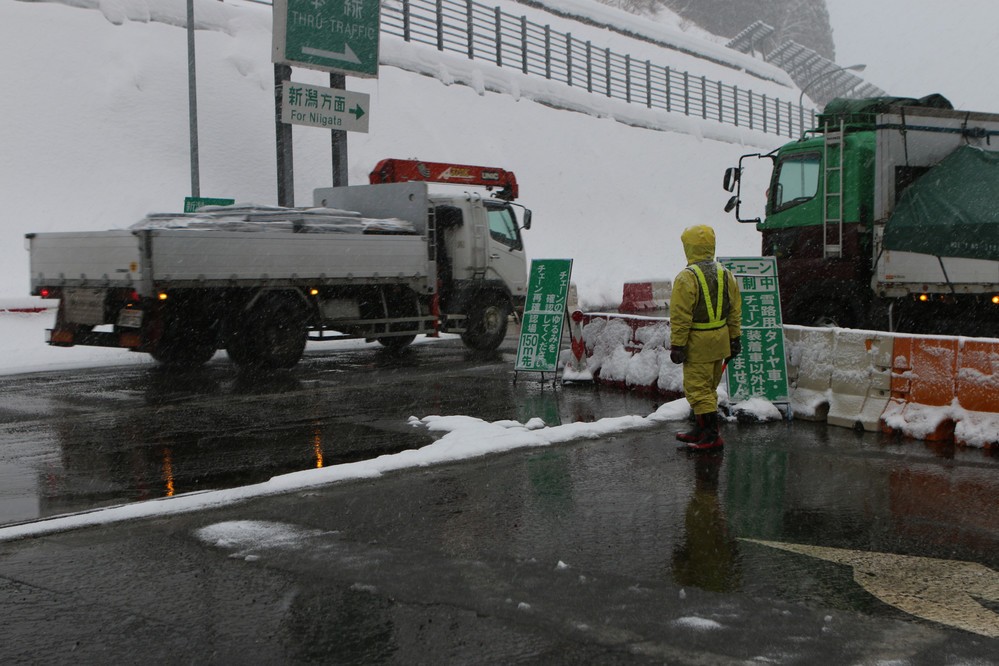 土樽PAのチェーン着脱場。係員が装着の有無をチェックしている。雪の中、黙々と誘導棒をふるう姿が印象的だった