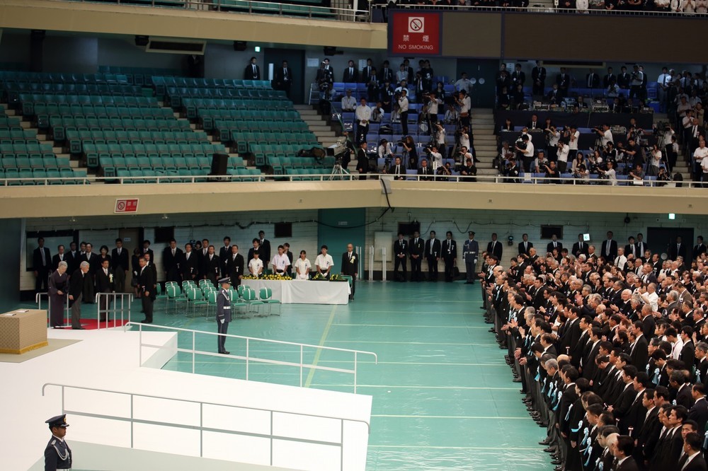 参列者席（写真右）から起こった拍手に見送られる形で、天皇皇后陛下（写真左）は式場を後にした