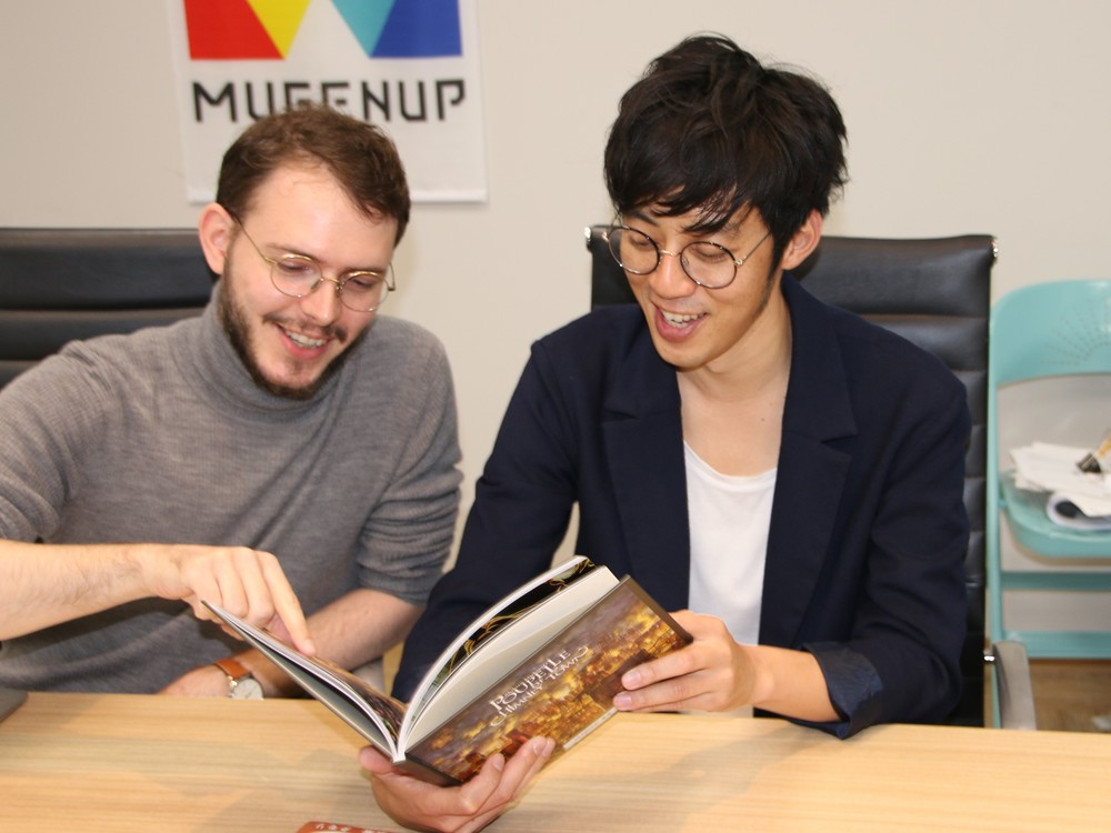 制作統括のペラン・アントワーヌ氏（左）と絵本を眺める