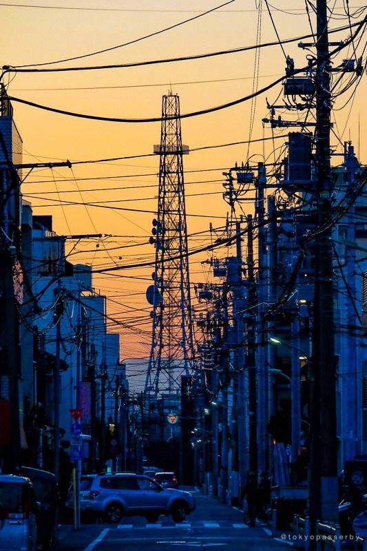 「tokyopasserby」（＠tokyopasserby）さんの投稿した写真。夕暮れの街に、電柱と鉄塔がそびえる