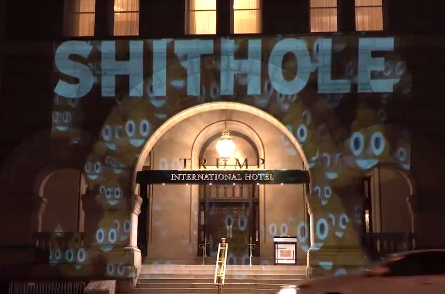 トランプ・インターナショナル・ホテルの正面に浮かび上がった「SHITHOLE」とウンコの形の笑顔の絵文字。2018年1月13日、ワシントンで。（Sorane Yamahira /  http://Bellvisuals.com） 