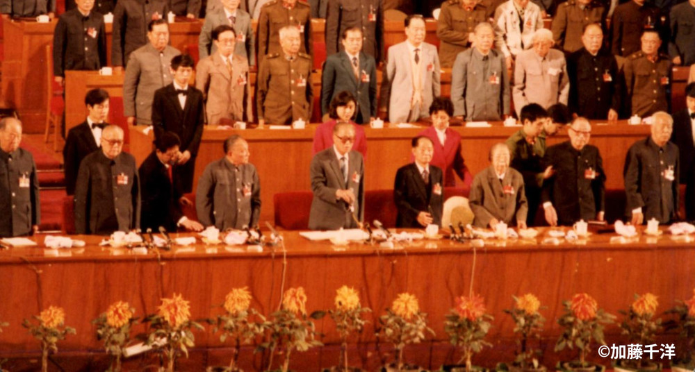 1997年秋の第13回党大会のひな段。最前列中央の趙紫陽総書記（右手をマイクに伸ばす）以外は第一線を退いたはずの長老たちばかり。鄧小平は趙の左隣）