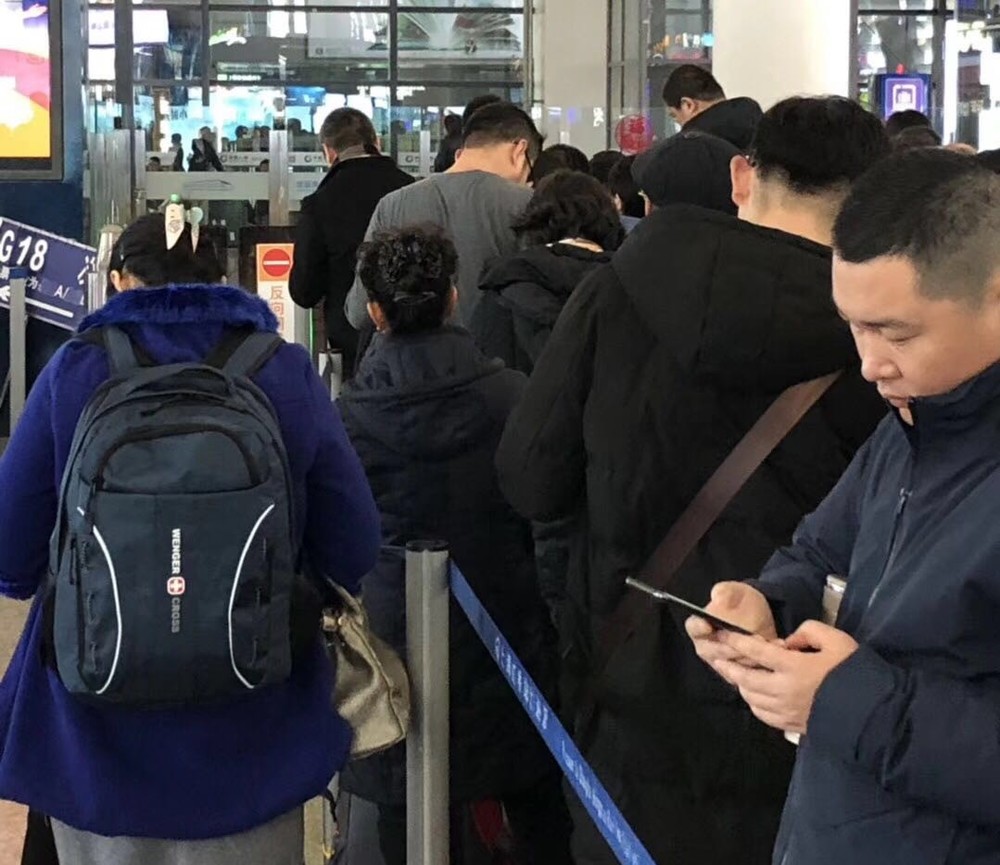 春節明け、上海駅切符売り場に並びながらスマホに見入る人たち