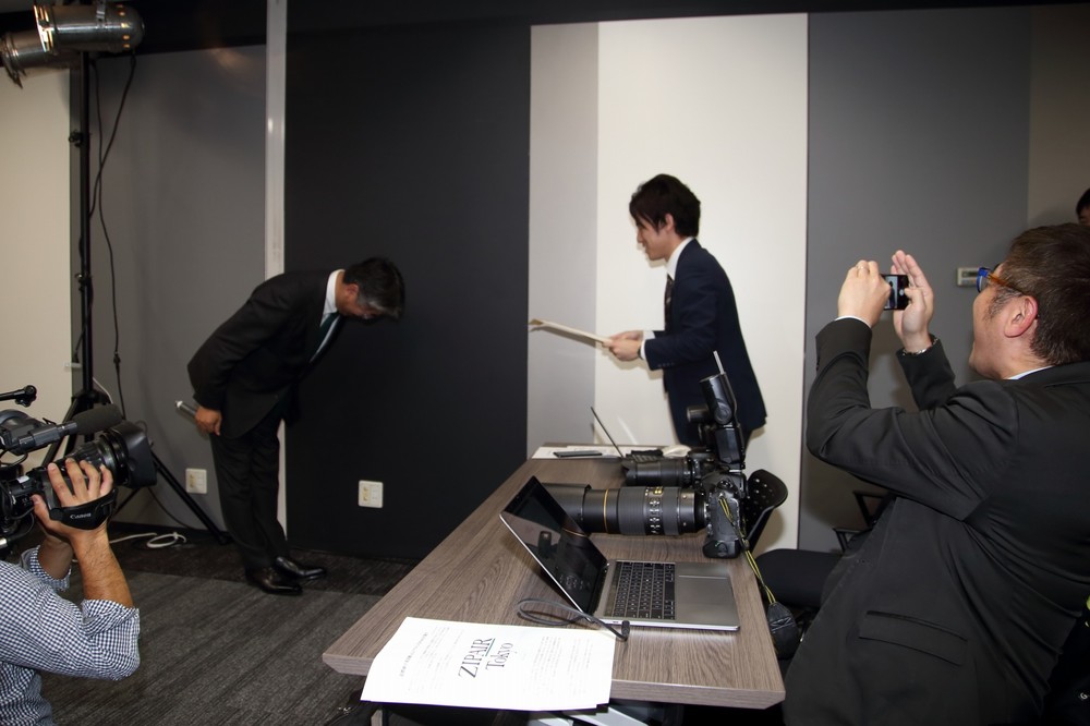 記者を「表彰」する西田真吾社長（左）