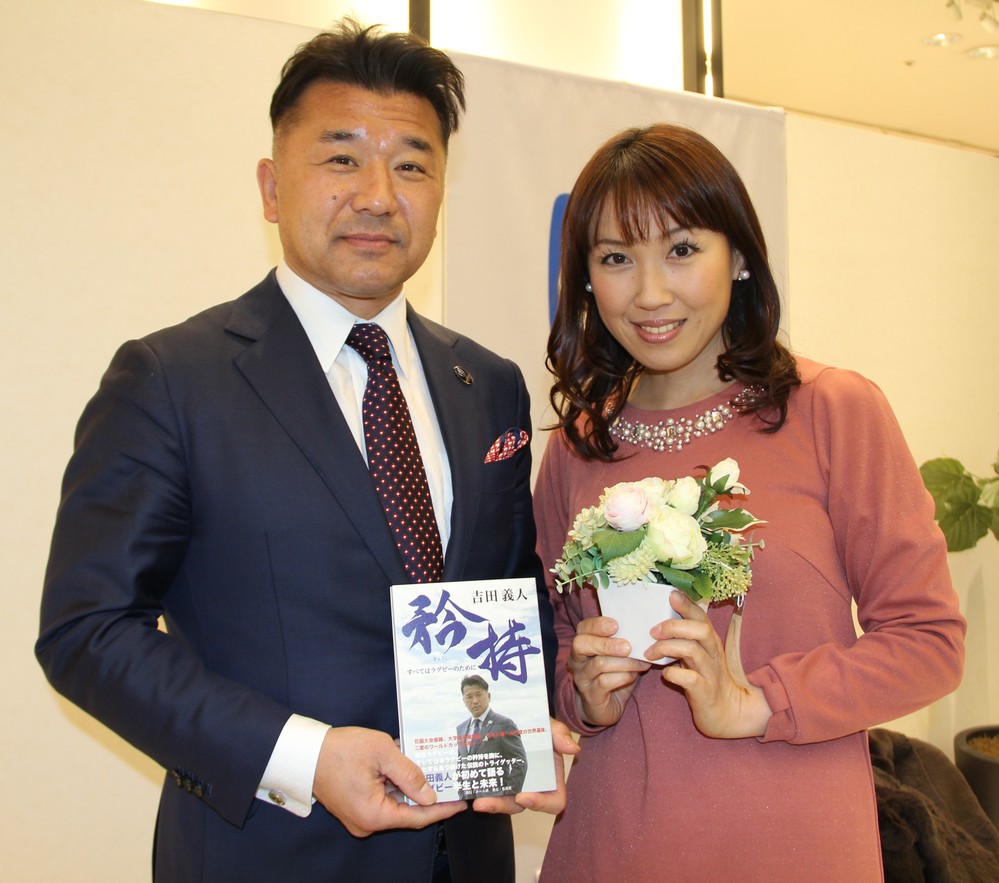 自身の著書「矜持」を手にする吉田義人氏と妻の亜里さん