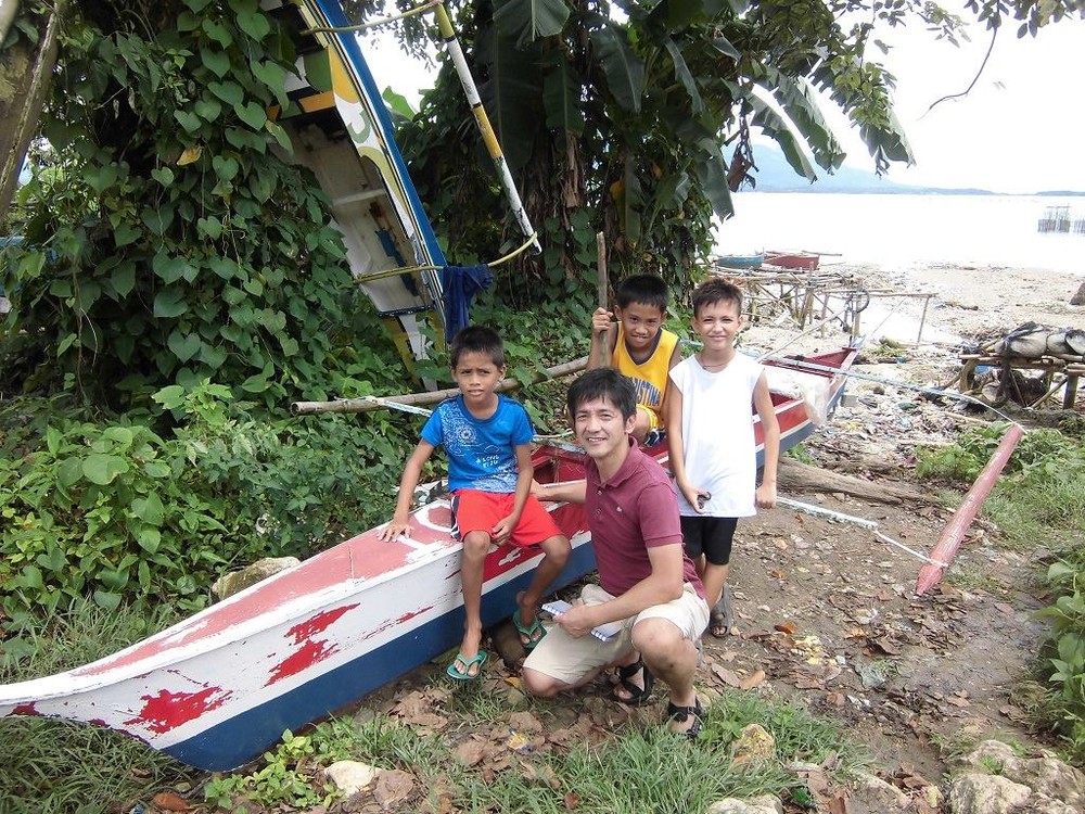 フィリピンの子どもたちと一緒に写る四倉禎一朗さん（写真提供：いしのまきNPOセンター）