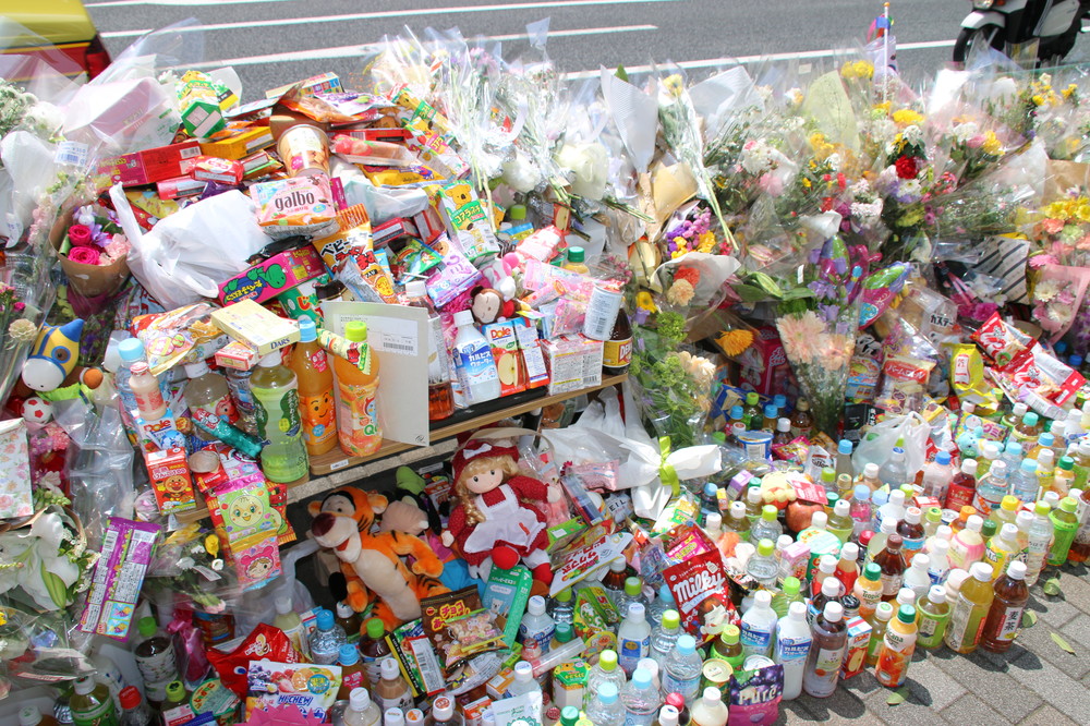 池袋の事故現場には、花束のほか菓子や飲み物なども続々と供えられた（2019年4月23日撮影）