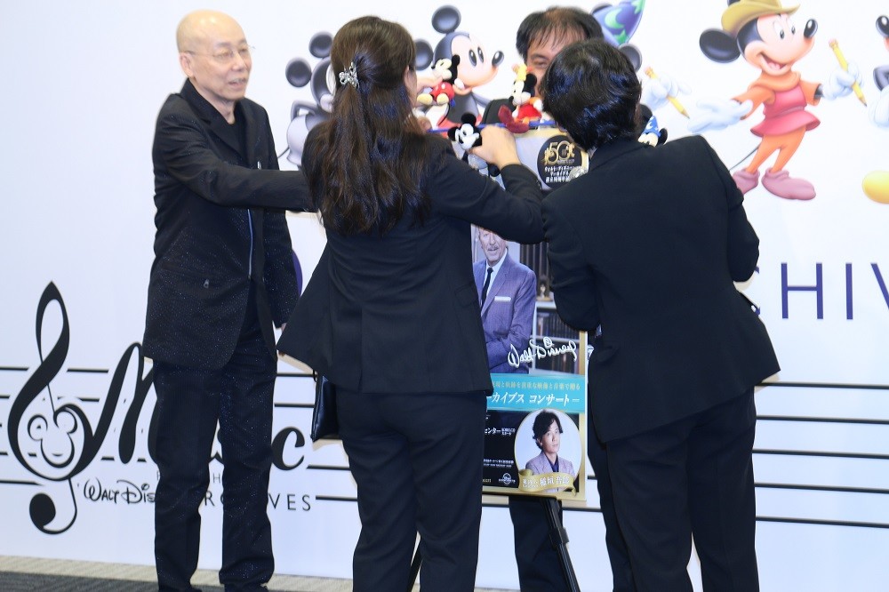 落下したミッキーマウスのぬいぐるみを拾い集めるスタッフと登壇者の島健さん（左）