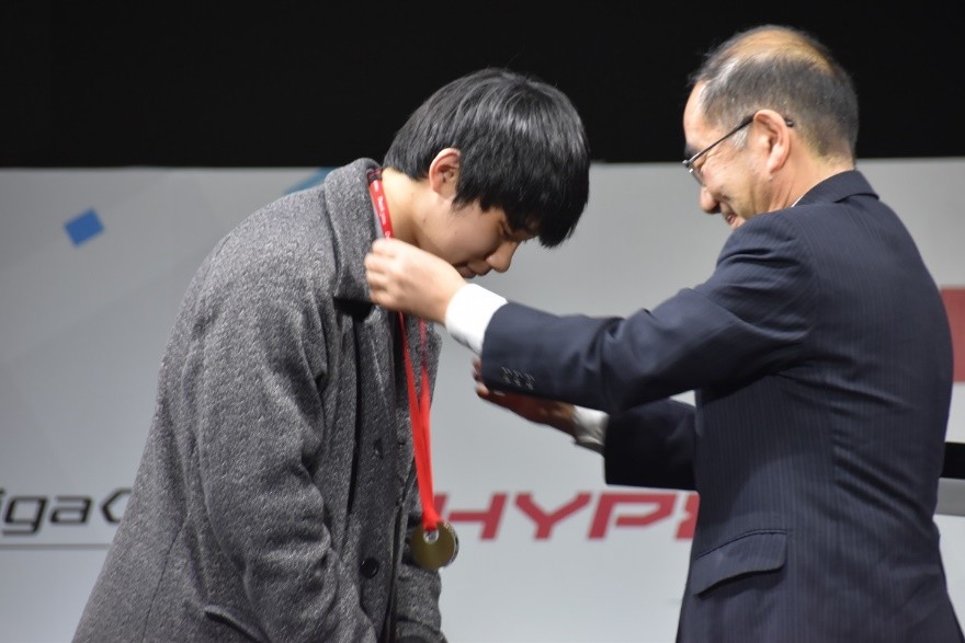 多羅尾光睦東京都副知事（右）からメダルを首にかけてもらう、やみえるぅ選手（左）