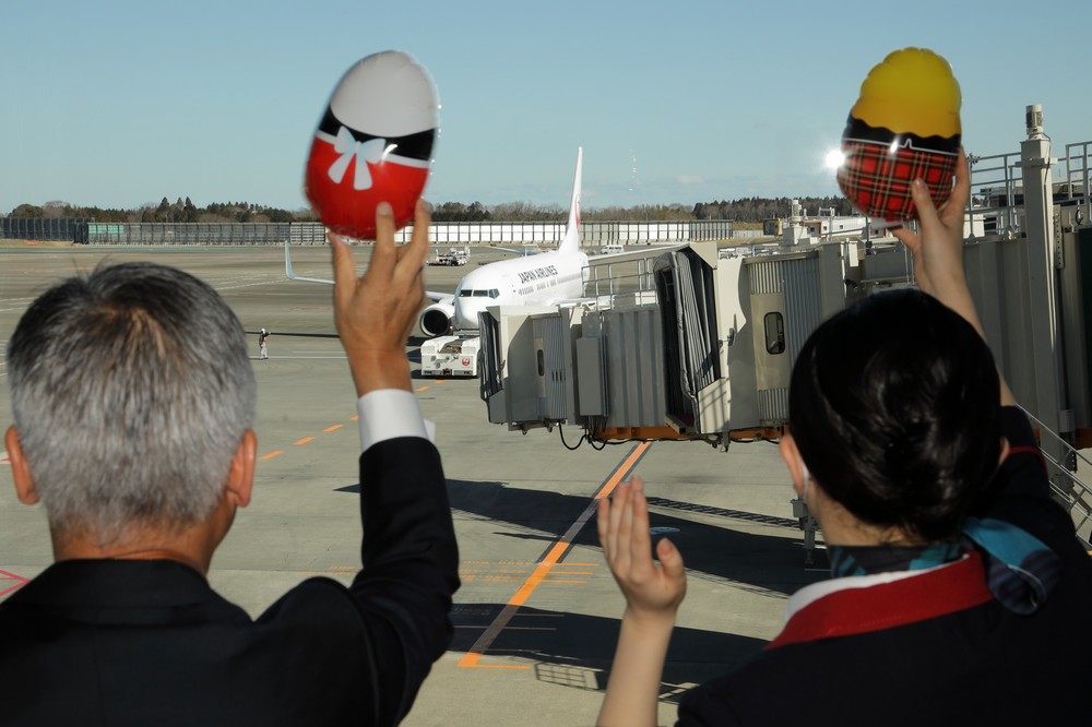 JALの藤田直志（ただし）副社長（写真左）らは、マトリョーシカ風の風船を手に初便を見送った